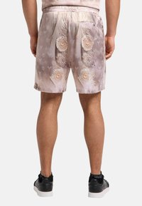 Shorts i mykt stoff, med en lys rosa og beige fargekombinasjon, intrikate sirkelmønstre og en baklomme.