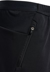 Schwarze Sportshorts mit strukturiertem Bund und einer Reißverschlusstasche an der Seite zur Aufbewahrung. Hergestellt aus dehnbarem Material.
