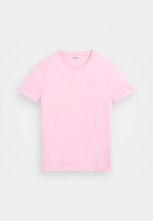 Rozā kokvilnas t-krekls ar īsām piedurknēm un apaļu kakla izgriezumu. Uz kreisā krūts apgabala ir neliels, gaiši zils logo. Mīksta tekstūra.