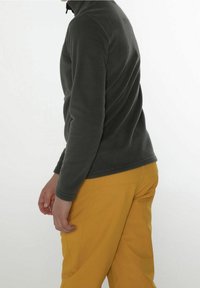 Jasna szara kurtka polarowa z wysokim kołnierzem, w połączeniu z żółtymi spodniami. Tkanina ma miękką teksturę i dopasowany krój.