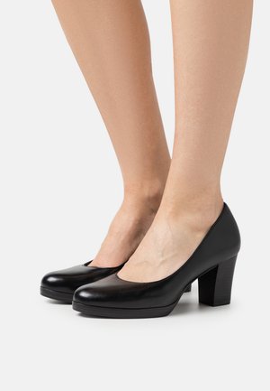 Chaussures en cuir noir à talons hauts avec bout arrondi, plateforme modérée et talon bloc robuste, présentant une surface lisse et polie.