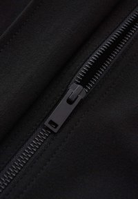 Schwarzer Stoff mit sichtbarem Reißverschlussdetail, das eine glatte Textur und ein mattes Finish aufweist. Der Reißverschluss ist schwarz mit metallischen Zähnen und hat einen rechteckigen Zipper.