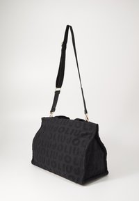 Borsa di stoffa nera con motivo a logo in rilievo, forma strutturata, dettagli in hardware dorato, tracolla regolabile e superficie testurizzata.