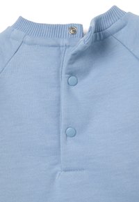 Pullover de algodón azul claro con un cuello de canalé, dos botones a presión y una textura suave. Presenta un diseño limpio y sencillo sin patrones.