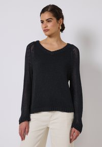 Maglione nero in maglia con scollo a V, maniche lunghe e polsini a coste; presenta una trama a rete e una vestibilità comoda.
