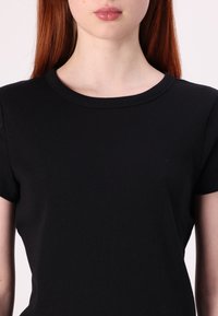 T-shirt nera a maniche corte con scollatura rotonda, caratterizzata da una texture liscia e una forma aderente, che enfatizza un design snello.