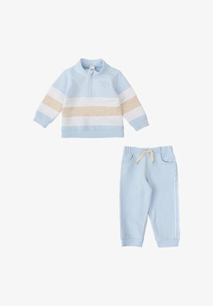 Sweat-shirt bleu clair avec zip, rayures blanches et beiges, logo brodé. Pantalons de jogging bleu clair assortis avec cordon de serrage et rayures sur les côtés.