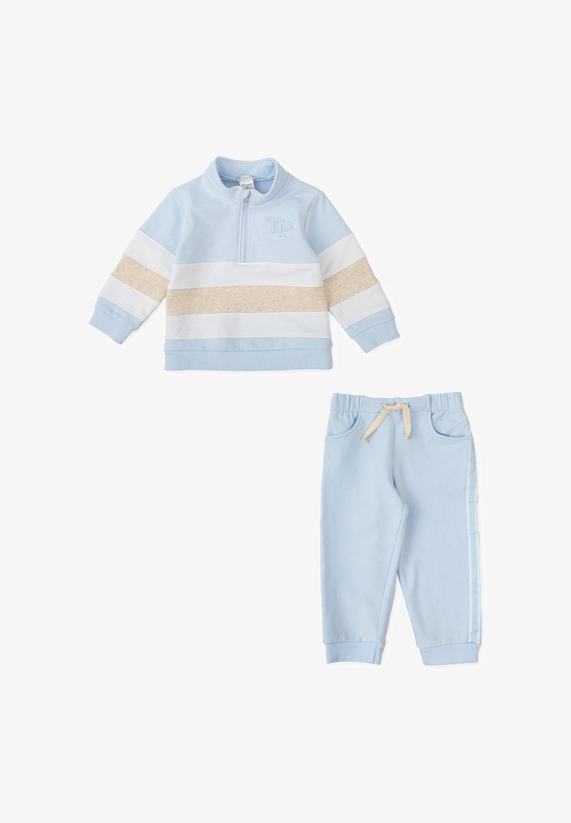 Sudadera azul claro con cremallera, rayas blancas y beige, logo bordado. Pantalones de chándal azul claro a juego con cuerda ajustable y rayas laterales.