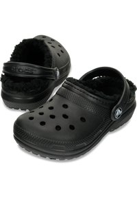 Zuecos negros con interior suave y esponjoso, cuentan con grandes orificios de ventilación, una correa trasera y una suela exterior de goma texturizada para mayor agarre.