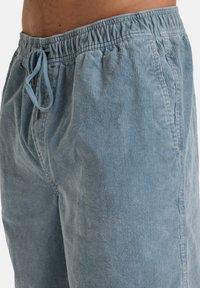 Shorts en velours côtelé bleu clair avec une coupe décontractée, taille élastique et fermeture à cordon. Caractérisés par une texture côtelée et un design simple.