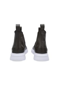 Zapatos de cuero marrón oscuro con paneles elásticos en los laterales, suelas de goma blanca y tiradores en la parte posterior. Textura suave y diseño elegante.