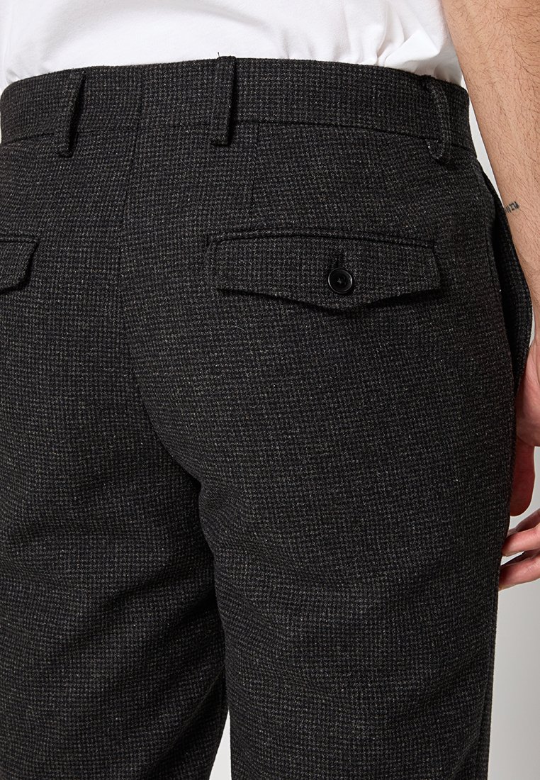 Schwarze, strukturierte Hose mit einem dezenten Muster, ausgestattet mit zwei Gesäßtaschen mit Knopfverschlüssen und einem geraden Beinschnitt.