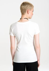 White short-sleeve t-shirt with a round neckline and a soft cotton texture, paired with a black accessory around the neck.