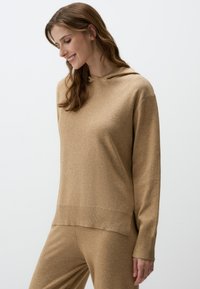 Felpa con cappuccio beige in morbido tessuto, caratterizzata da una vestibilità comoda e maniche lunghe. Leggera trama melangiata con orlo e polsini a coste.