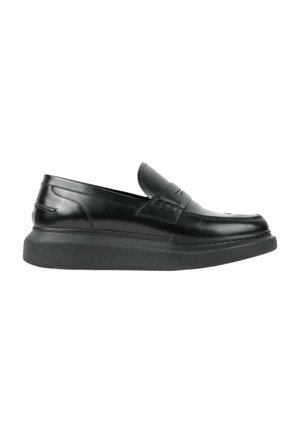 Mocassin en cuir noir avec une semelle épaisse texturée et un détail de bride décorative sur le dessus, vue de côté sur fond blanc.