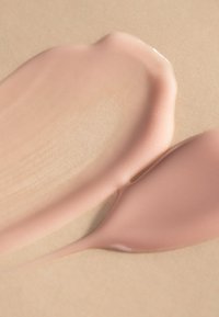 Due tonalità cremose e testurizzate di rosa chiaro e nude morbido su uno sfondo beige liscio, che mette in evidenza una finitura lucida e una sottile lucentezza.