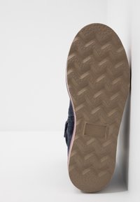 Ciemnoniebieska podeszwa buta z teksturowanym, gumowym uchwytem. Charakteryzuje się wzorem w zygzak oraz jasnym wykończeniem krawędzi. Płaski profil dla stabilności.