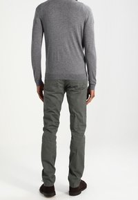 Mörkgröna bomullsbukser i kombination med en åtsittande grå tröja, som visar en enkel design och texturerad tyg, med synliga sömmar.