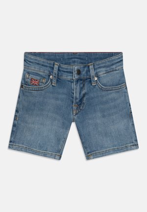 Short en denim bleu avec bouton devant, passants pour ceinture, poches avant, et un petit écusson du drapeau britannique sur la poche droite.