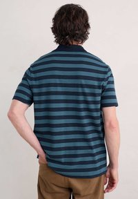 Polo à manches courtes rayé en marine et turquoise, avec un col côtelé et une coupe décontractée. Tissu doux avec un motif texturé.