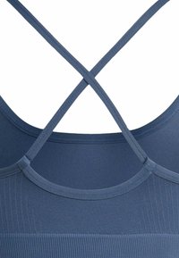 Brassière de sport en tissu côtelé bleu avec fines bretelles croisées dans le dos et un design lisse et sans coutures.