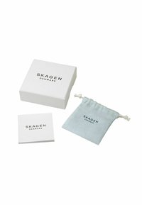 Scatola bianca di orologi Skagen Denmark, libretto delle istruzioni piegato e sacchetto azzurro chiaro con cordoncino e testo del logo in nero.