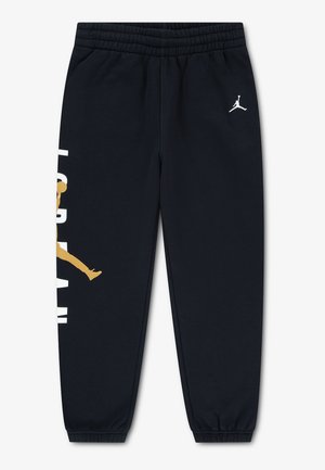 Jogging noir à taille élastique avec logo Jordan blanc sur la cuisse droite et grand graphique Jumpman or et blanc sur la jambe gauche.