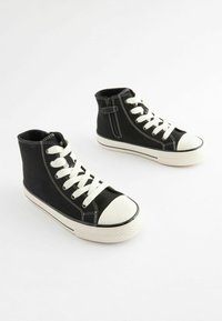 Czarne sneakersy do kostki na płaskiej podeszwie z białymi sznurówkami, gumowymi czubkami i akcentami w szwach; posiadają zamek błyskawiczny z boku dla łatwego zakładania.