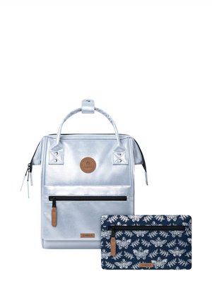 Silberner Rucksack mit Frontreißverschlusstasche und oberen Griffen, kombiniert mit einem dunkelblauen Täschchen mit Blumen- und Schmetterlingsmuster und einer Frontreißverschlusstasche.