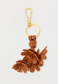 Καφέ δερμάτινο μπρελόκ με σύμπλεγμα διακοσμητικών φύλλων, συνδεδεμένο με μεταλλικό κλιπ χρυσού τόνου και κυκλικό κρίκο κλειδιών.