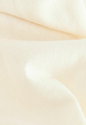Tela color crema con una textura de punto suave y fino, que muestra variaciones sutiles en el grosor y una caída suave. Sin patrones ni acentos.
