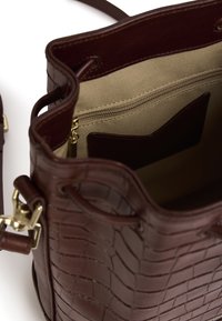 Borsa a secchiello in pelle marrone con texture coccodrillo, hardware dorato e un interno beige chiaro che presenta una tasca con zip e uno slot aggiuntivo.
