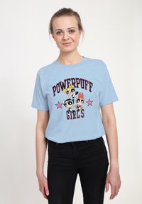 Světle modré bavlněné tričko se grafikou tří kreslených postaviček a textem "Powerpuff Girls" s růžovými hvězdnými akcenty.