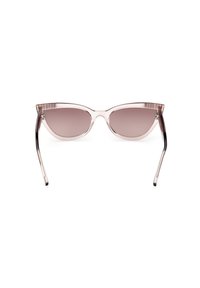 Gafas de sol cat-eye transparentes de color rosa con lentes marrones degradados, bisagras de metal y patillas ligeramente curvadas sobre un fondo blanco.