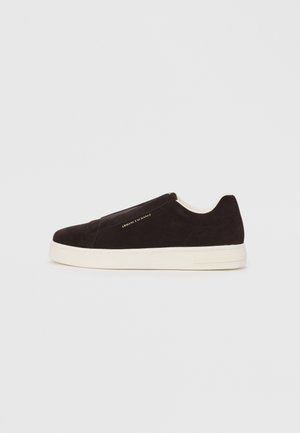 Zwarte suède instapsneaker met witte rubberen zool, met een gladde textuur en subtiele branding aan de zijkant. Klassiek ontwerp en structuur.