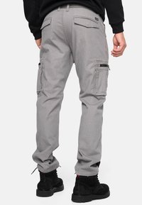 Pantalon cargo gris avec plusieurs poches, poignets élastiqués et une poche zippée. Fabriqué en tissu durable, avec une coupe décontractée et des jambes droites.