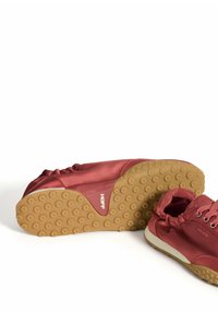 Zapatillas de satén rojo con suela de goma texturizada. Las características incluyen una parte superior suave, puntera redondeada y sistema de cordones. Con acento de un logo.
