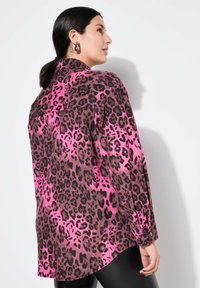 Rosa Leopardenmuster-Shirt mit langen Ärmeln, das einen spitzen Kragen, einen abgerundeten Saum und knöpfbare Manschettenmerkmale aufweist. Glatte Stofftextur.