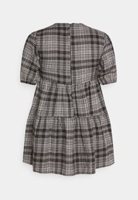 Robe à manches courtes à carreaux noirs et blancs avec jupe à volants et poignets élastiqués, vue de dos sur un fond blanc.