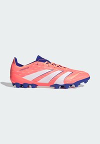 Scarpa da calcio rosa brillante con una superficie testurizzata, strisce bianche e suola blu. Progettata per offrire trazione su superfici erbose.