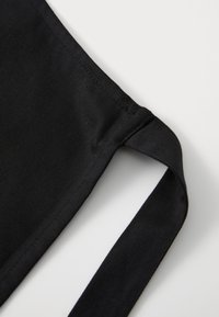Svart bikini topp i stoff med en jevn tekstur, med en sidestrikk og enkelt design. Sømmen er pent og minimal.