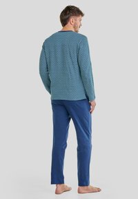 Conjunto de lounge para hombre que incluye una camiseta de manga larga azul con estampado y pantalones azules a juego, con una textura suave y un corte relajado.