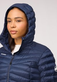 Marine blauwe pufferjack met capuchon, voorzien van een gequiltde textuur, voorrits en "Mammut"-logo. Glad, lichtgewicht materiaal.