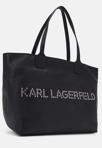 Sac fourre-tout en cuir noir avec deux poignées et « KARL LAGERFELD » écrit en clous argentés sur le devant.