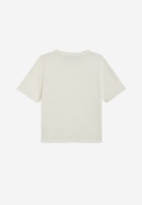 T-shirt a maniche corte di colore crema, realizzato in cotone morbido. Presenta una vestibilità ampia, scollatura rotonda e dettagli di cucitura minimi.