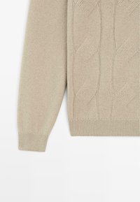 Beiger Strickpullover mit Zopfmuster, gerippten Bündchen und Saum. Weiche Textur, lange Ärmel und leicht lockere Passform.