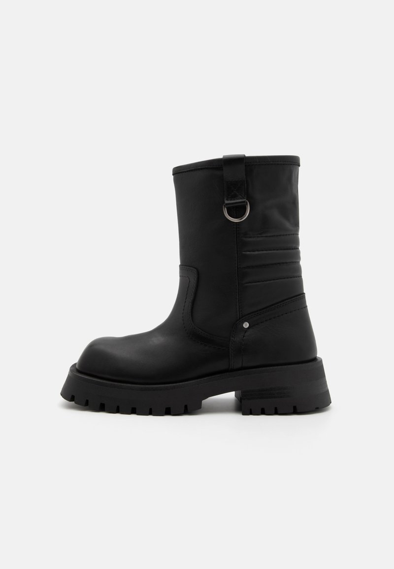 Stivale alla caviglia nero realizzato in pelle liscia con un pannello laterale testurizzato, un accento ad anello e una suola in gomma resistente per una migliore aderenza.