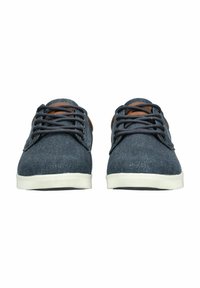 Sneakers di denim blu scuro con dettagli in pelle marrone. Presentano una punta rotonda, design con lacci e suola in gomma bianca con dettagli testurizzati.