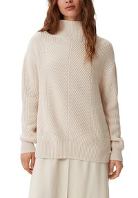 Helle beigefarbene Strickjacke mit hohem Kragen, strukturiertem Muster, lässiger Passform sowie gerippten Bündchen und Saum. Mit dezenten Details akzentuiert.