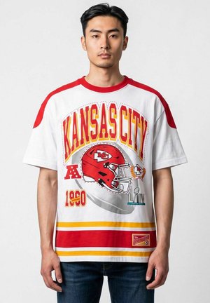 Giovane uomo che indossa una maglia da football bianca e rossa dei Kansas City Chiefs con grafica di casco e stemma del Super Bowl LIV.